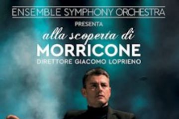 direttore d'orchesta nell'atto di dirigere e sullo sfondo i musicisti