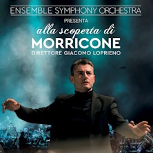 direttore d'orchesta nell'atto di dirigere e sullo sfondo i musicisti