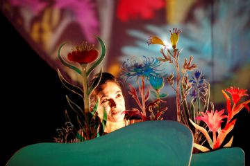 volto di donna tra fiori cartonati e onde verdi