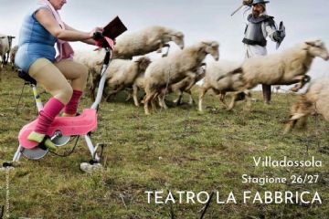 In un prato donna su cyclette con scaldamuscoli pedala su di una cyclette leggendo un libro poggiato sul manubrio. Sullo sfondo un gregge di pecore e un cavaliere con armatura